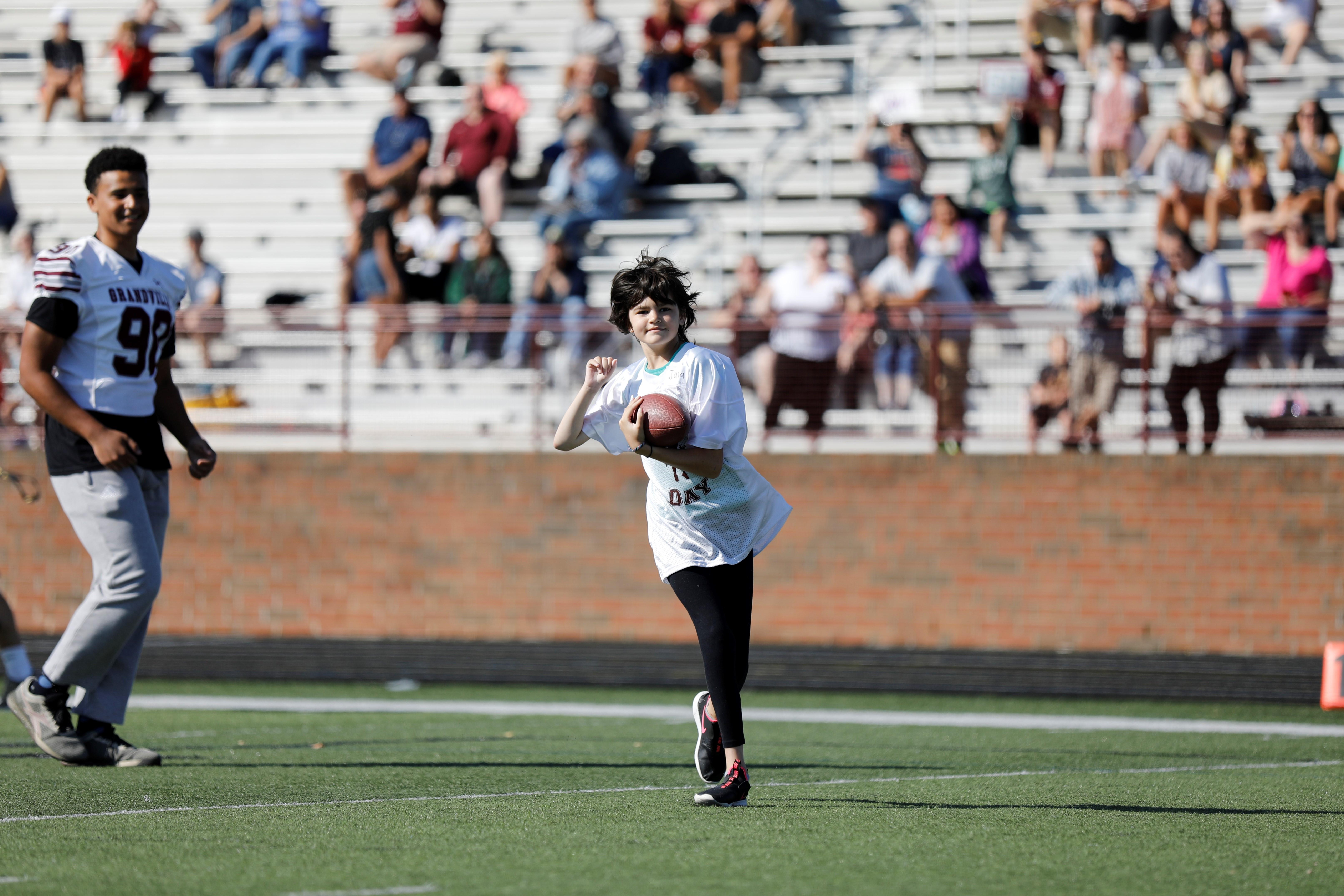 student running with football on field